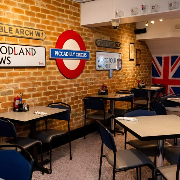Interior of Go Fish! restaurant with brick walls, London street signs, and blue chairs at tables.