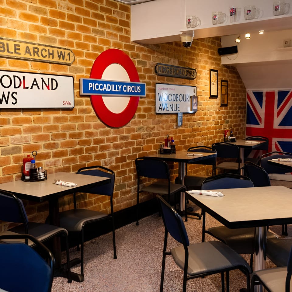 Interior of Go Fish! restaurant with brick walls, London street signs, and blue chairs at tables.
